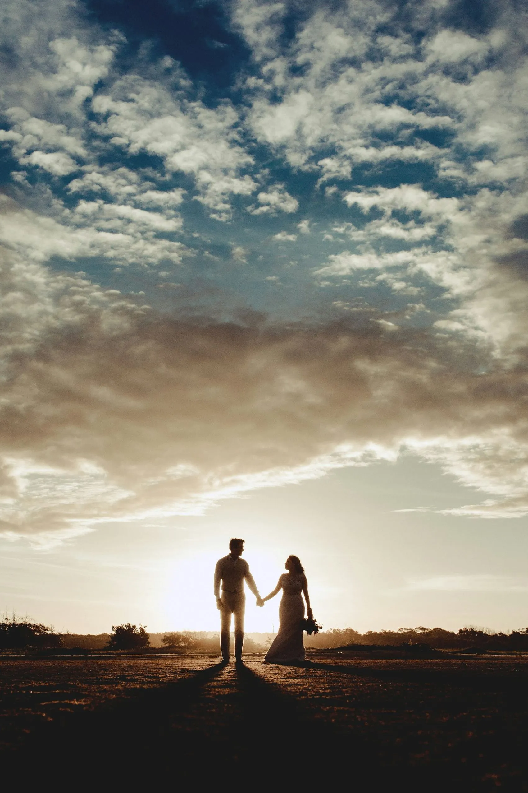 A couple silhouetted against a bright coastal sky