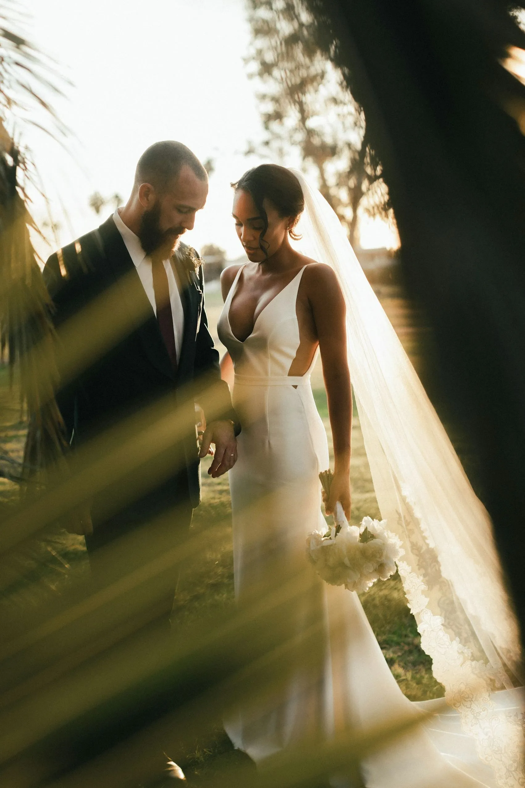 A couple photographed through foliage in warm light