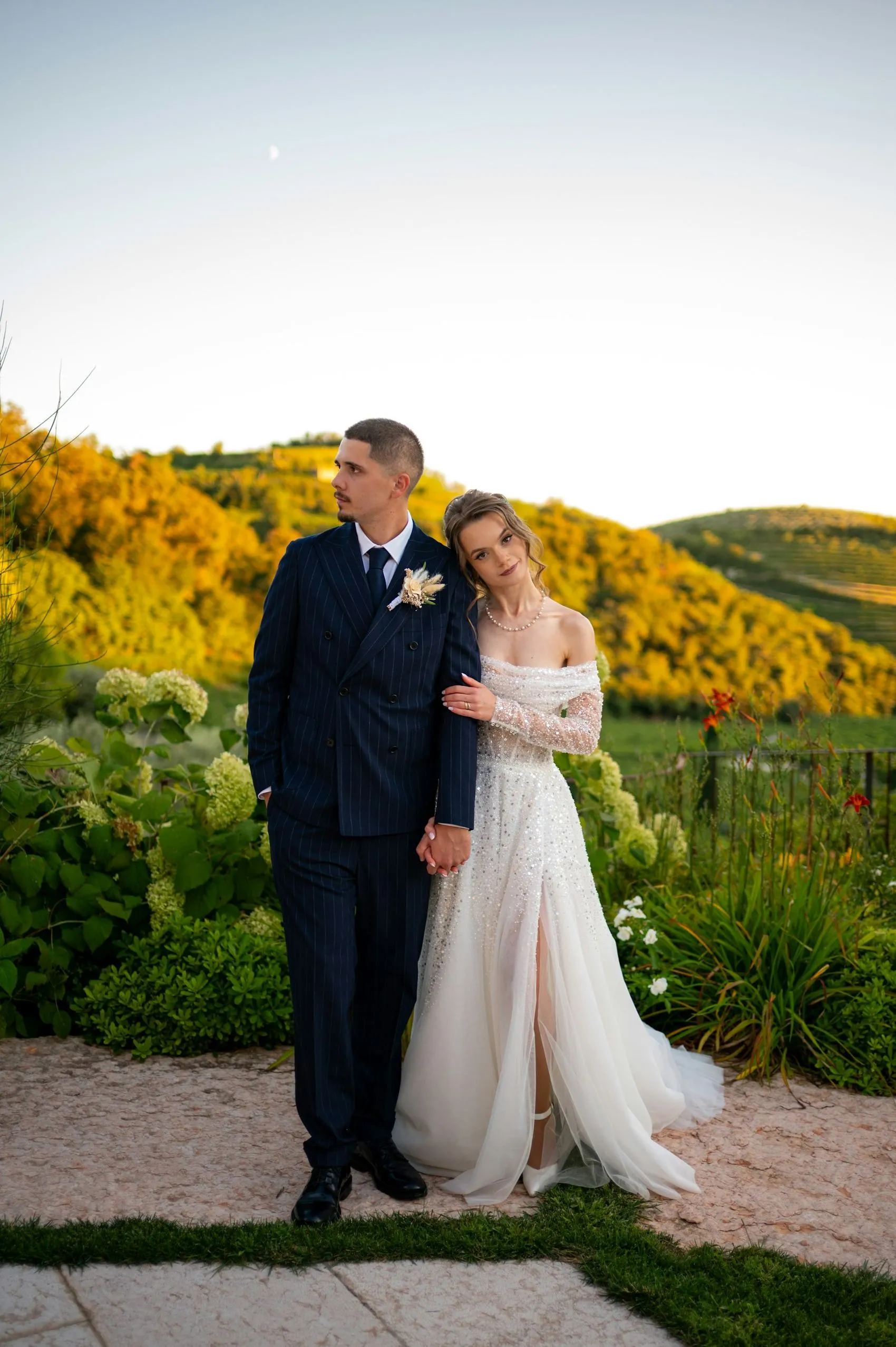 A couple standing together in the vineyard hills at dusk